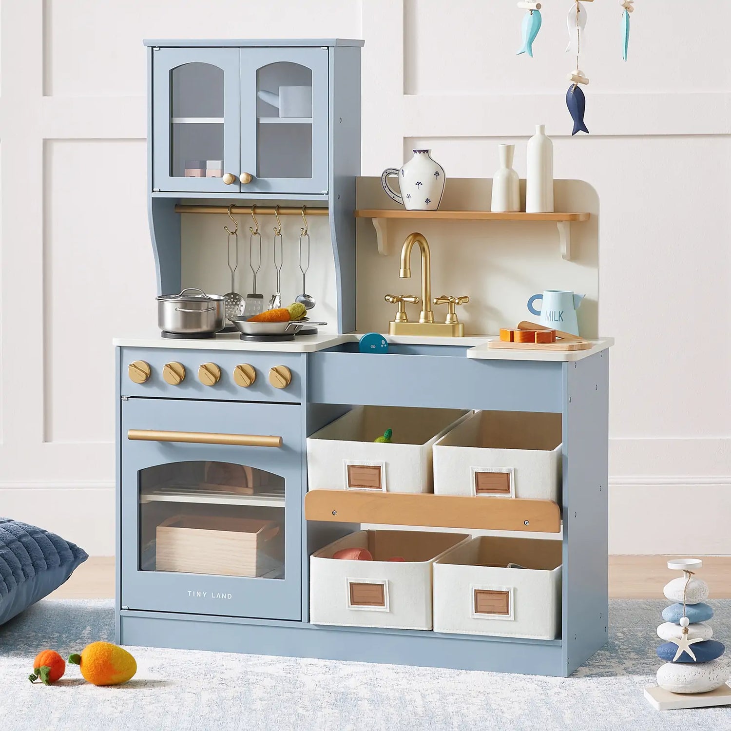 Tiny Land blue wooden play kitchen with sink, stove, gold faucet, hanging utensils, cookware, and organized storage bins