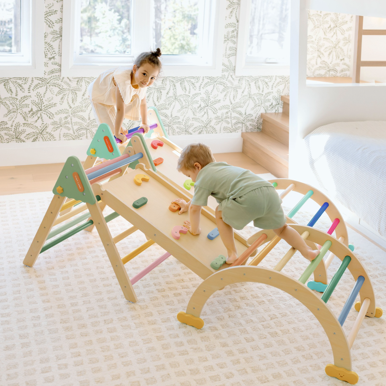 “Toddler playing on climbing wooden toys Montessori Pikler triangle set indoors”