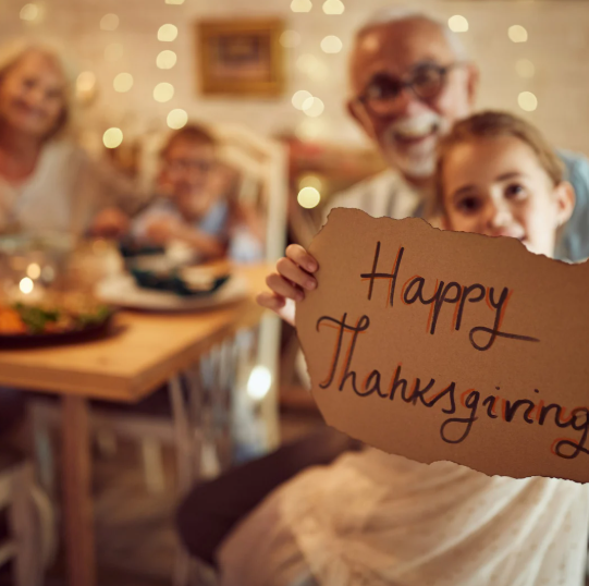 a whole family is sitting around the table to celebrate Thanks Giving Day together
