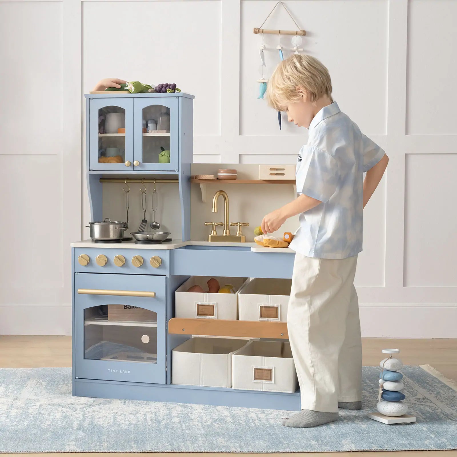 a boy is playing with his blue play kitchen in his playroom