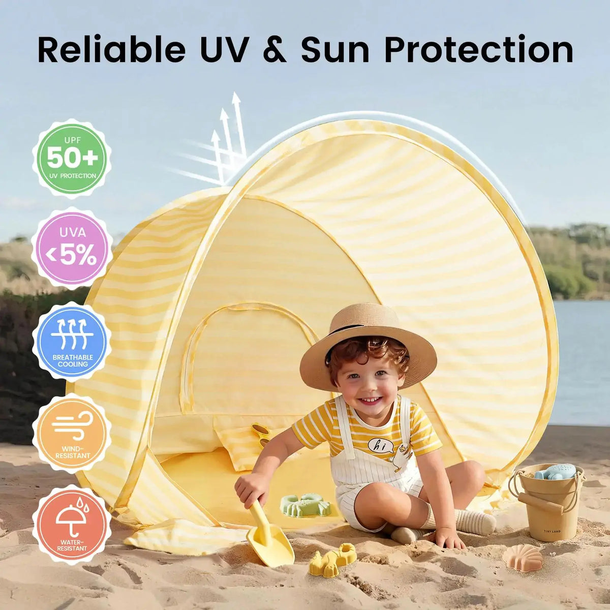A young child with a hat plays on the sand with a yellow shovel from the Tiny Land® One-Stop Beach Toy & Tent Set, in front of its yellow-striped tent. Icons show UV50+ sun protection, breathable fabric, wind and water resistance from Tiny Land.|Pastel Yellow Stripes