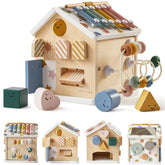 The Tiny Land® Cottage Activity Cube - Morandi by Tiny Land is a house-shaped wooden Montessori toy with a xylophone, bead maze, shape sorter, spinning gears, and colorful blocks. Four images display this fun developmental cube from various angles.