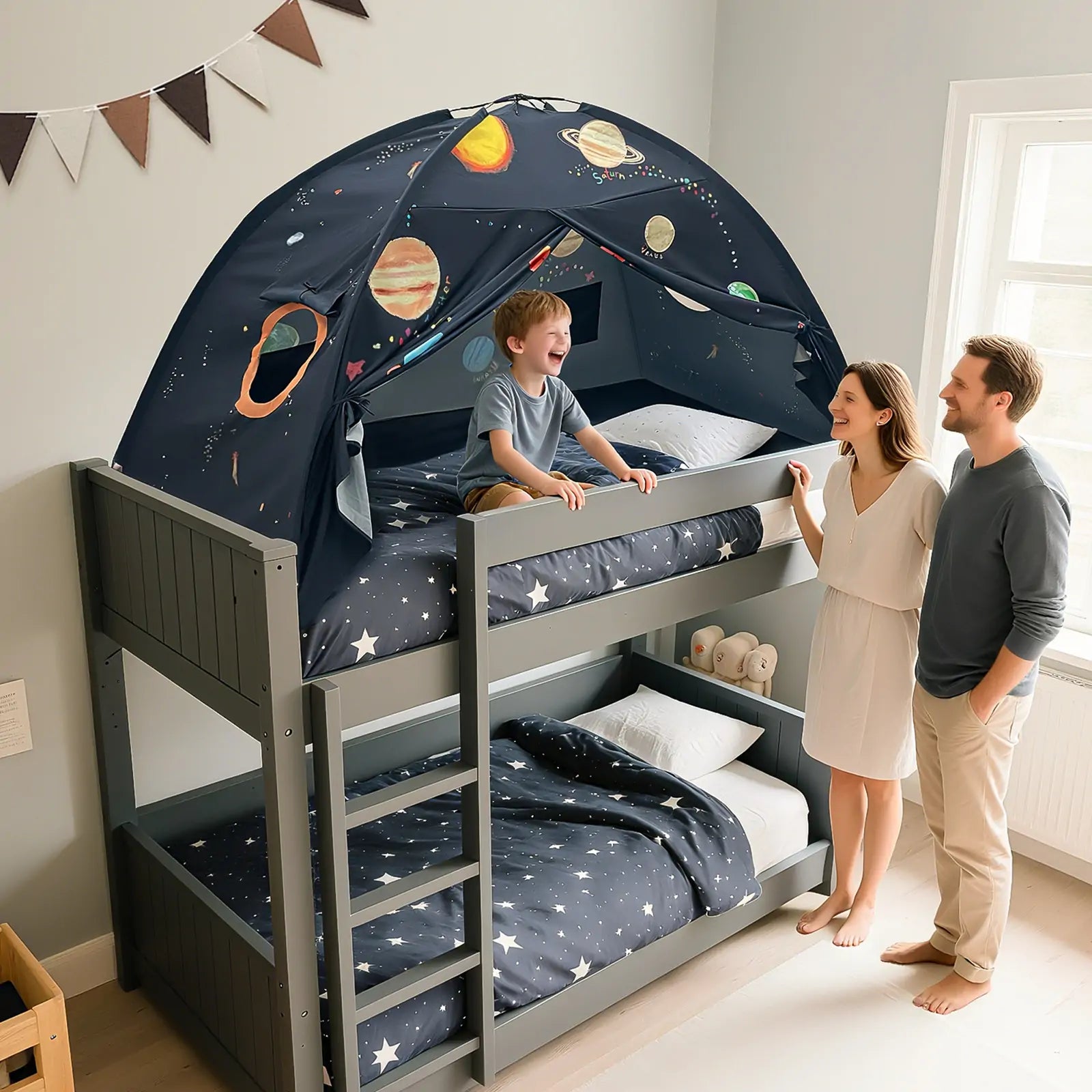 A smiling child enjoys the Tiny Land® SpaceNest Bed Tent by Tiny Land INC atop a gray bunk bed, turning it into an indoor adventure fort, while two adults stand nearby in a star-themed bedroom.