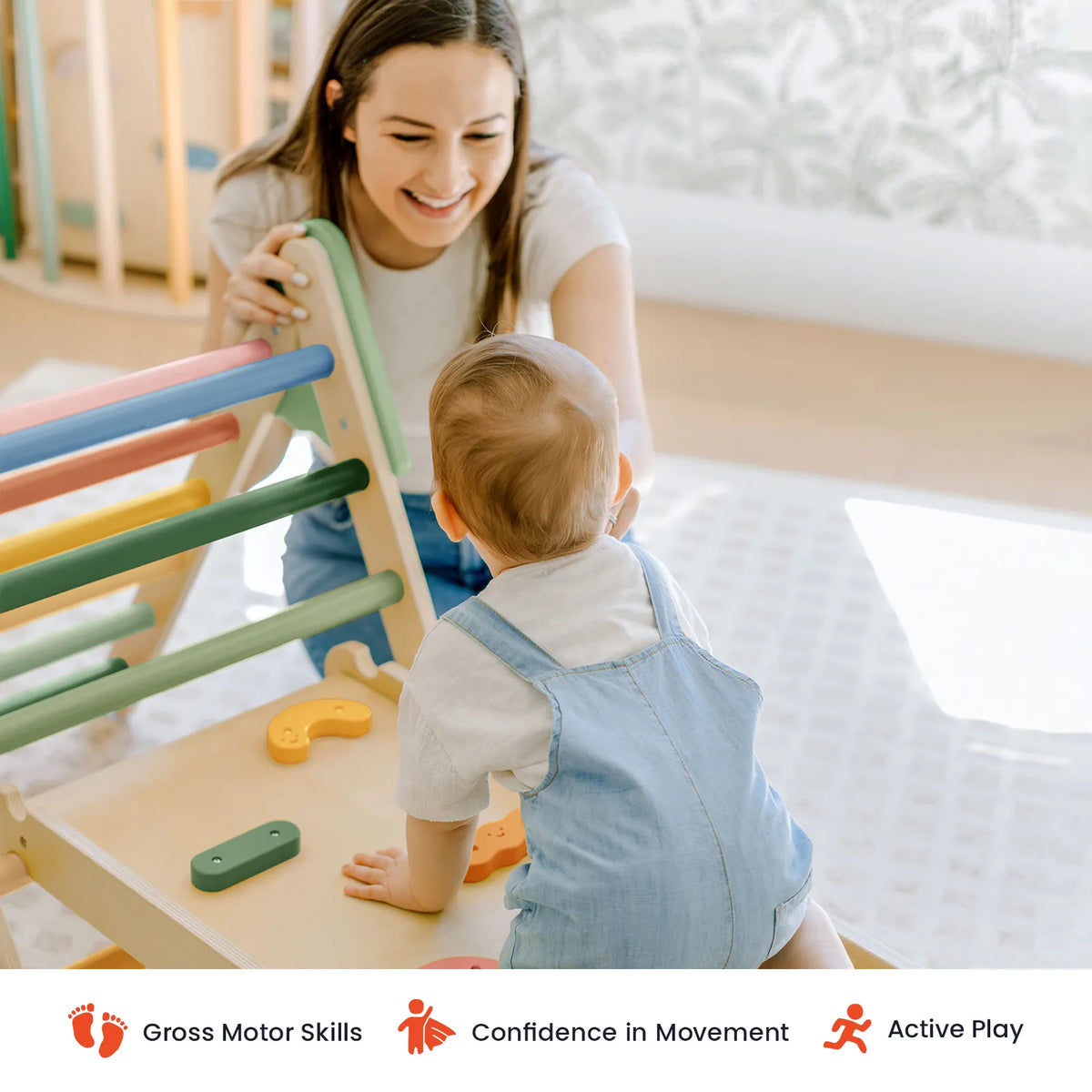 A smiling woman encourages a toddler as they explore the Tiny Land® 7-in-1 Morandi Pikler Triangle Set indoors. Icons below highlight benefits: gross motor skills, confidence in movement, and active play—making these toddler climbing toys from Tiny Land an ideal choice for fostering development.