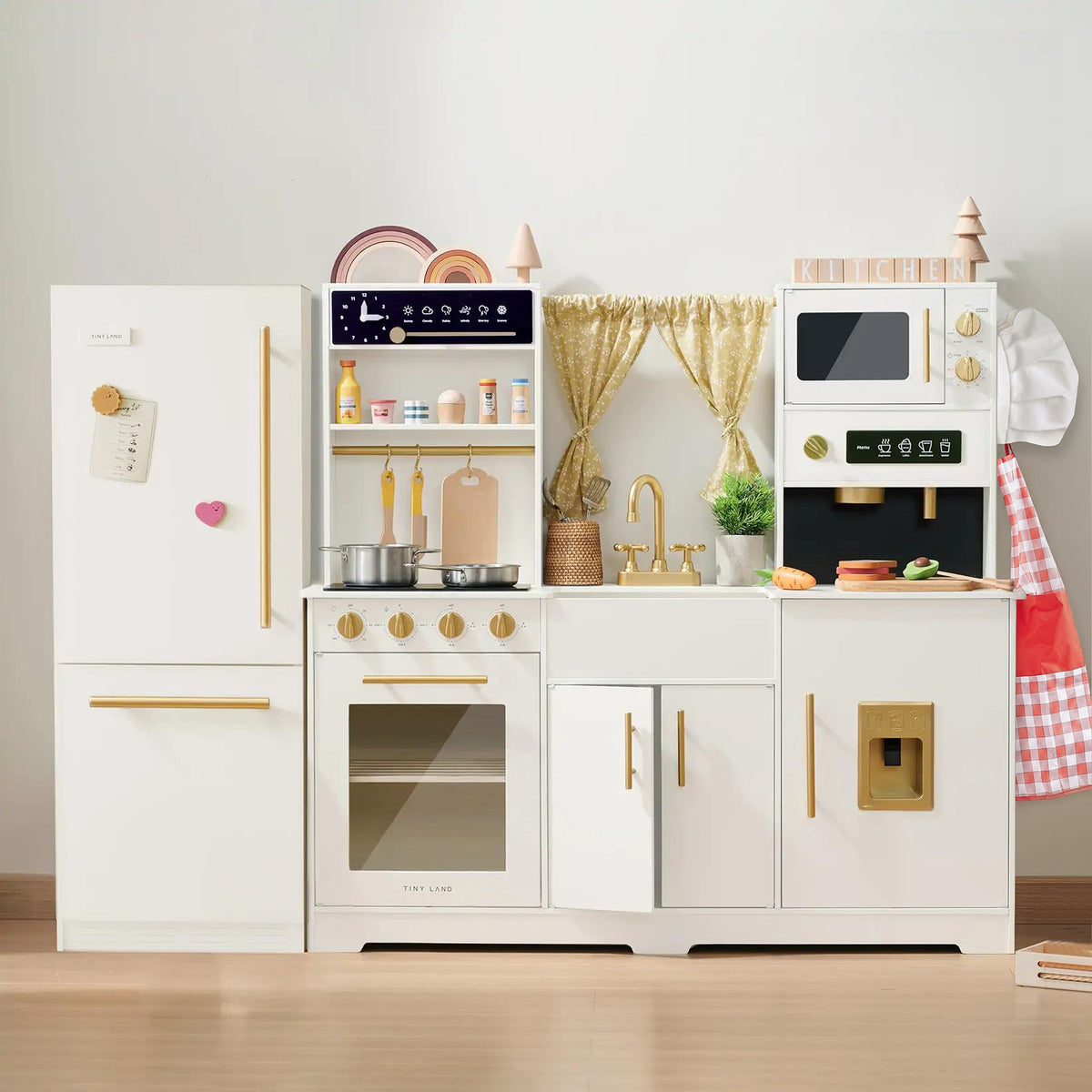Kids will love the Tiny Land® Premium Play Kitchen & Fridge Set by Tiny Land, a charming wooden play kitchen featuring a fridge, oven, stove, microwave, and sink. This set includes accessories such as pots, pans, kitchen tools, and colorful toy food for hours of imaginative fun. Finished in white with gold handles and vibrant toy items, this pretend play kitchen inspires creativity in every young chef.