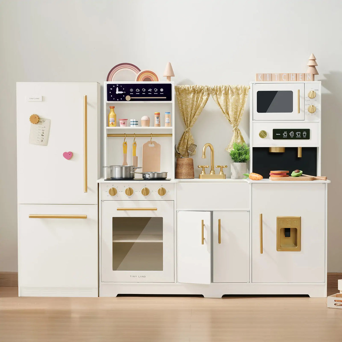 The Tiny Land All-in-One Family Feast Gift Set features a luxury kitchen and fridge with organic food, including a stove, oven, sink, microwave, cupboards, and accessories—perfect for kids who love imaginative cooking play.