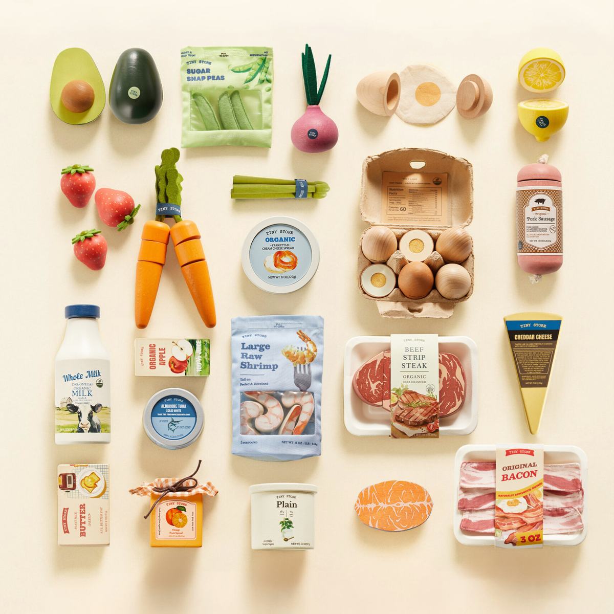 The Tiny Land® Organic Play Food Collection by Tiny Land INC features neatly arranged wooden play foods—vegetables, fruits, milk, shrimp, steak, eggs, cheese, bacon, honey, and yogurt—displayed in a grid on a light background.