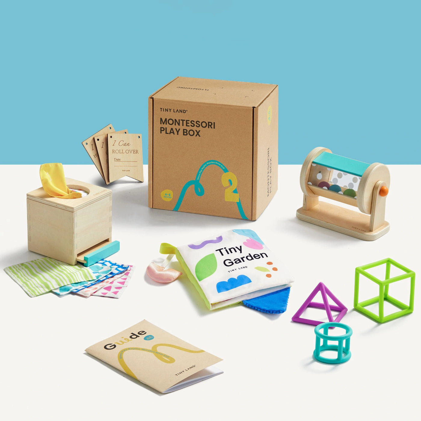 The Tiny Land Brain & Hands Playset — Montessori Box (4–6 Months) + Activity Cube includes a cardboard box, wooden tissue box, rattle, soft cloths, stacking shapes, booklets, and play cards—displayed on a white background.