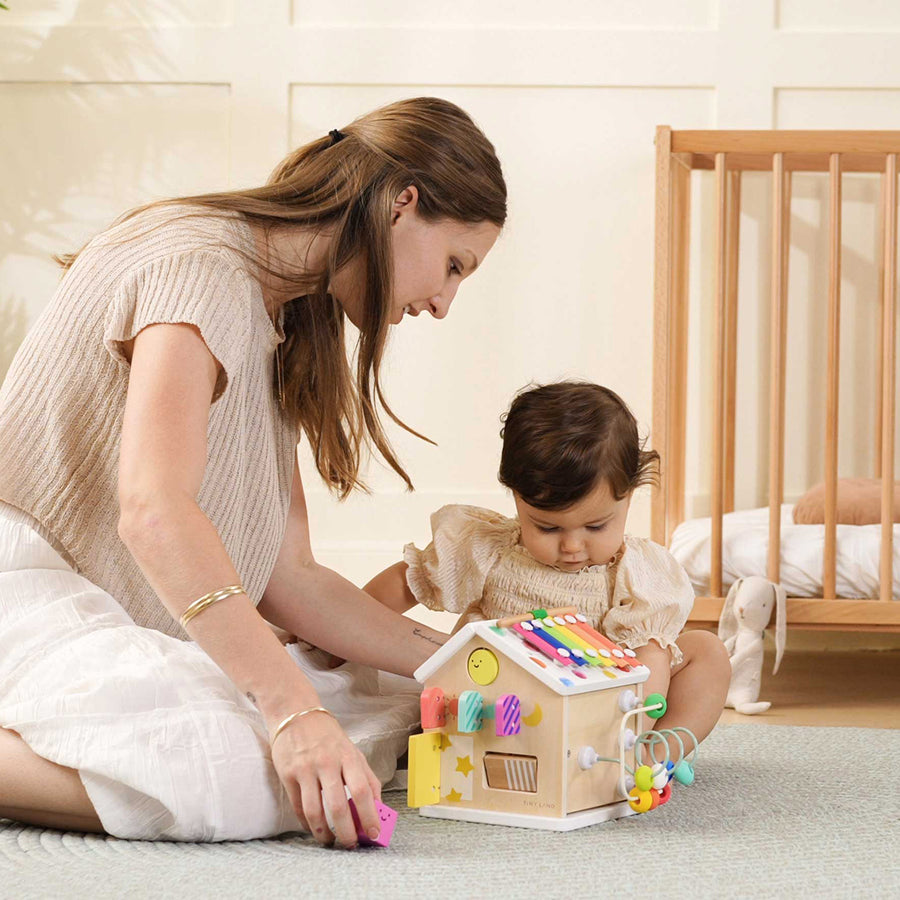 A woman and baby enjoy the Tiny Land Rainbow Baby Walker & Activity Cube Developmental Playset, sparking laughter and helping develop fine motor skills.