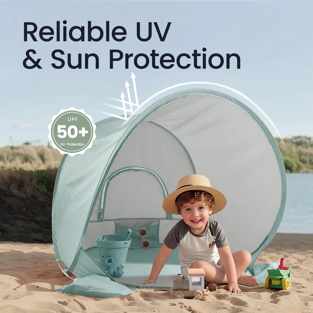 A smiling child in a sunhat enjoys the Tiny Land® One-Stop Beach Toy & Tent Set – Sea Blue, sitting in the tent with sand tools by water and greenery. Image text: Reliable UV & Sun Protection, UPF 50+ UV Protection. Brand: Tiny Land.|Sea Blue