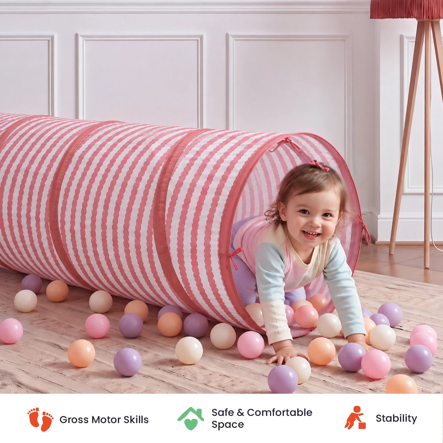 A toddler crawls out of a pink and white striped Tiny Land® Adventure Play Tunnel surrounded by colorful plastic balls, with icons below for Gross Motor Skills, Safe & Comfortable Space, and Stability.|Pink