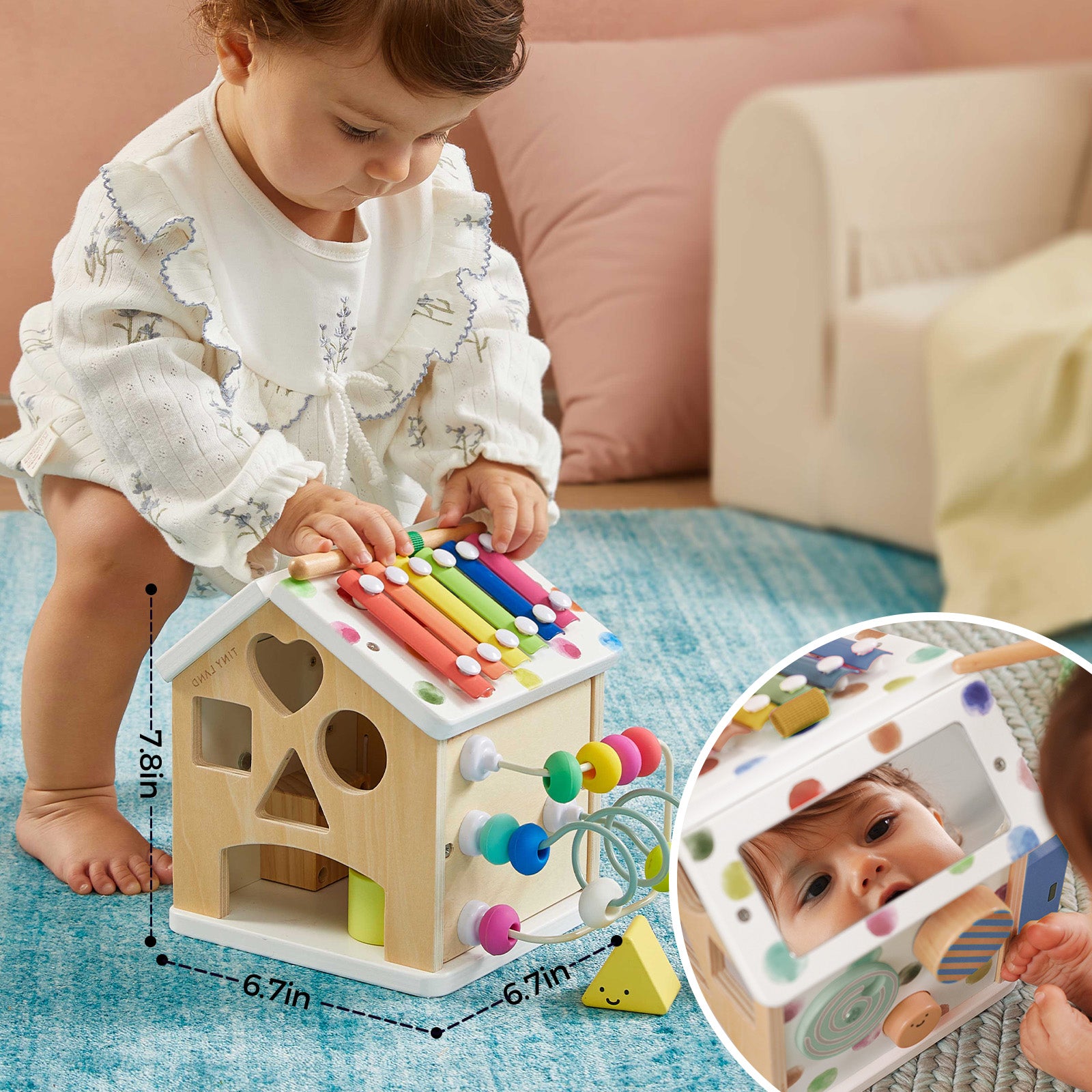 A baby plays with the Tiny Land® Cottage Activity Cube - Rainbow by Tiny Land, a developmental toy featuring a xylophone, bead maze, and shape sorter on a blue rug. An inset shows the baby looking into the cube's mirror. Dimensions are displayed.