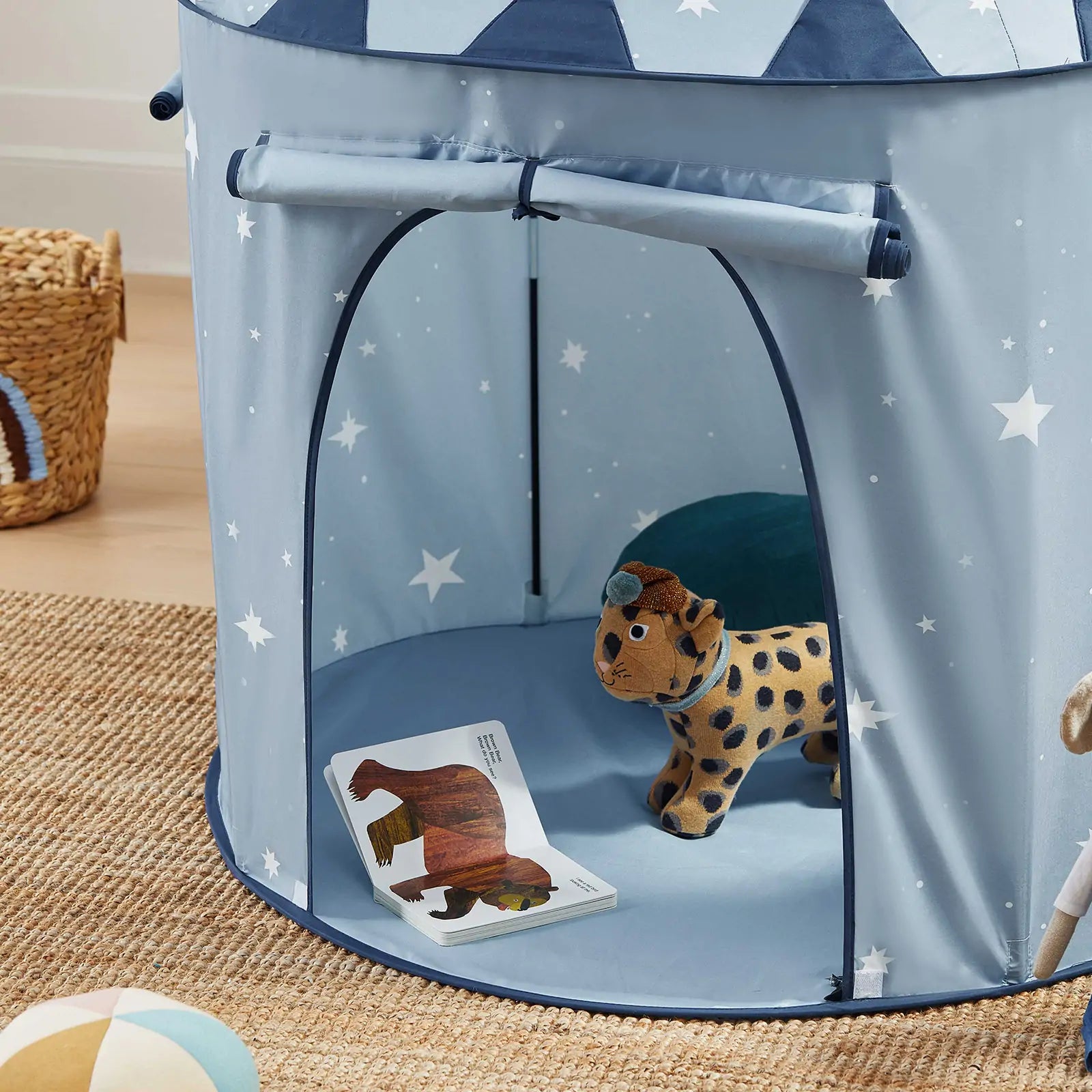 The Tiny Land® Kids Tent – Starry Blue Indoor Tent for Toddlers by Tiny Land sits on a woven rug with a plush cheetah toy and an open bear picture book inside. A basket and soft toys nearby make it perfect for fun indoors or outdoors.