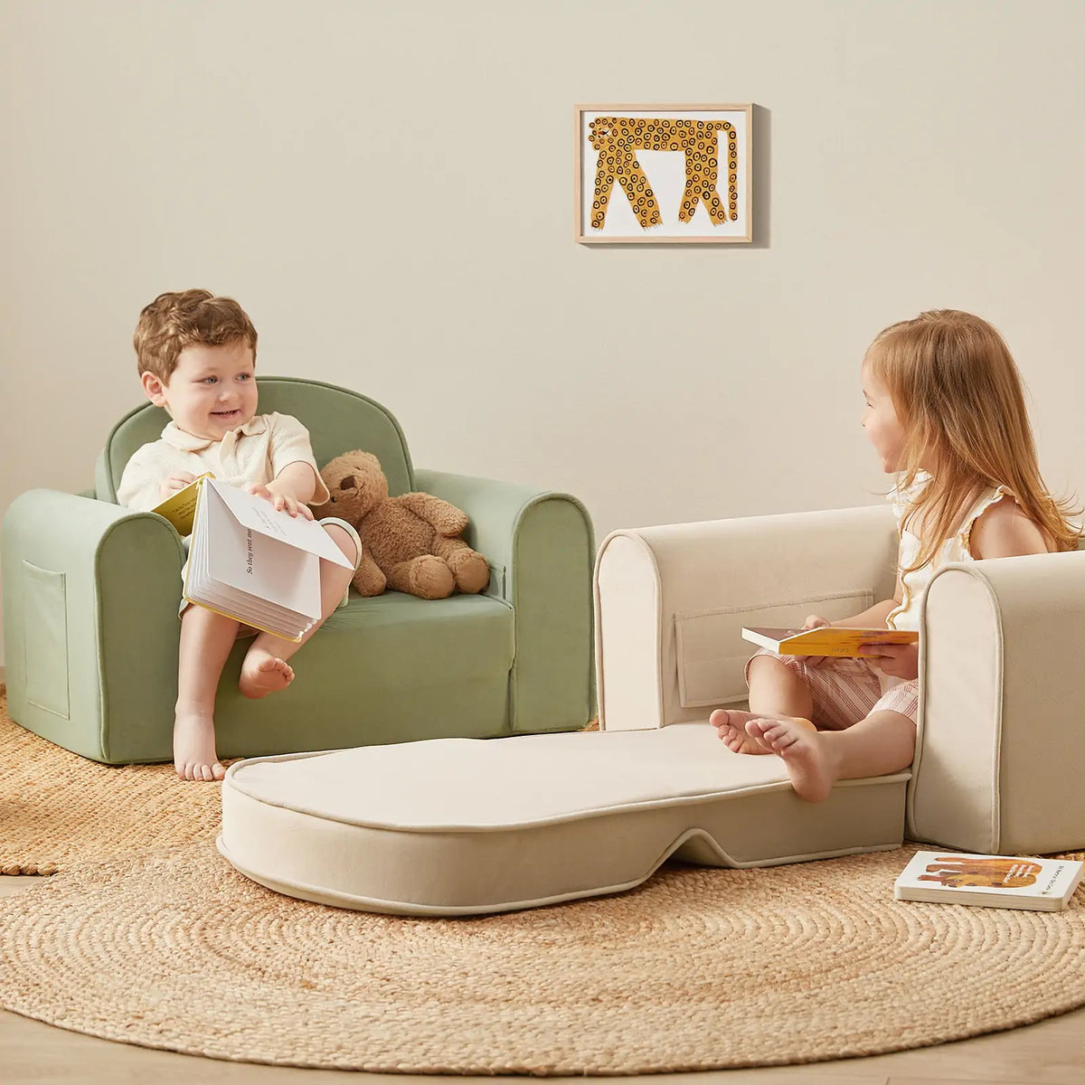 Two young children sit on the Tiny Land® GentleSnug Kid Chair - Beige White, reading books and smiling in a cozy room with a circular rug, neutral decor, a plush bear toy, and animal-themed wall art. Brand: Tiny Land.