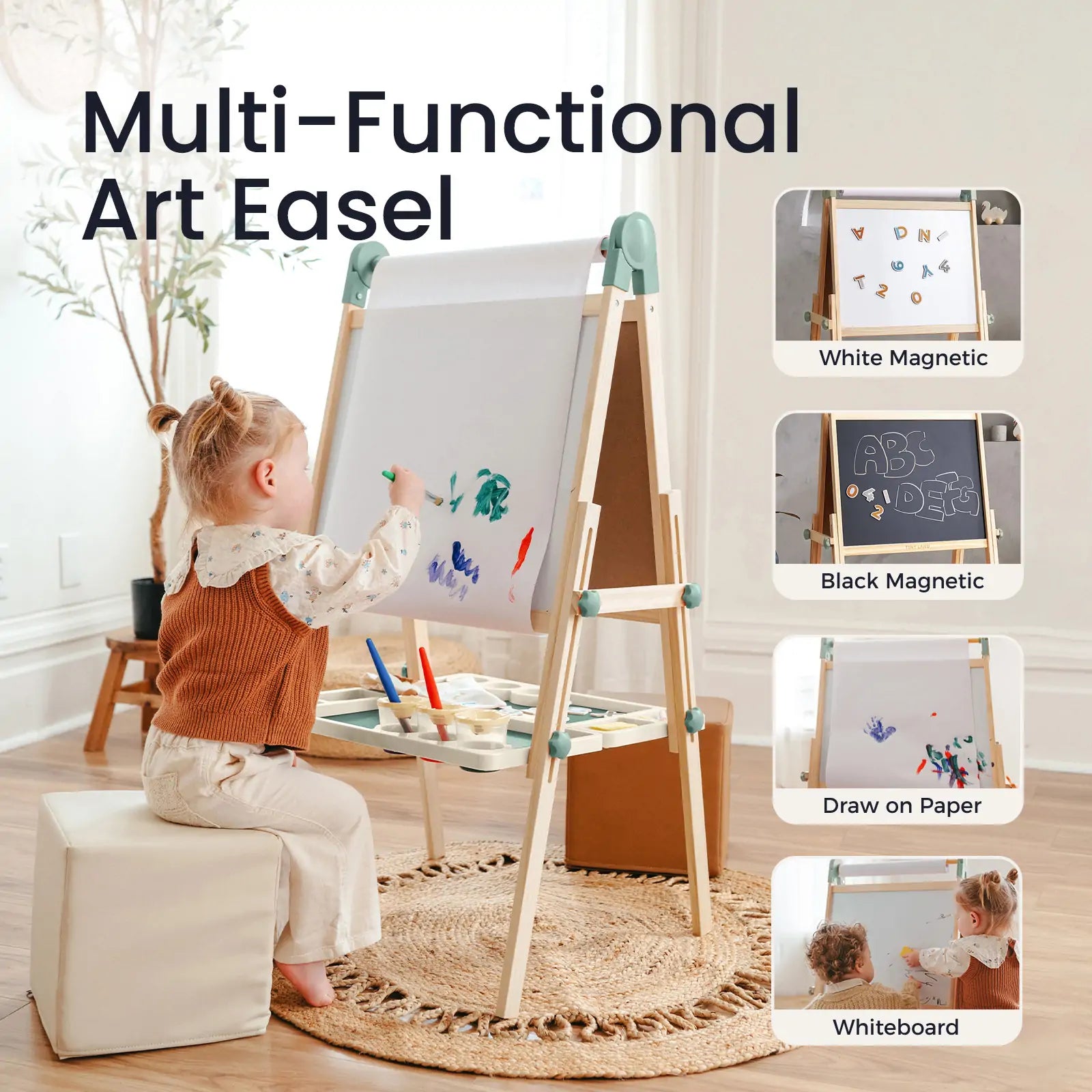 A young child sits on the Tiny Land® Magnitales Easel for Kids - Green, drawing with paint. This Tiny Land easel offers white and black magnetic boards, paper and whiteboard options, plus a tray for organized art supplies.
