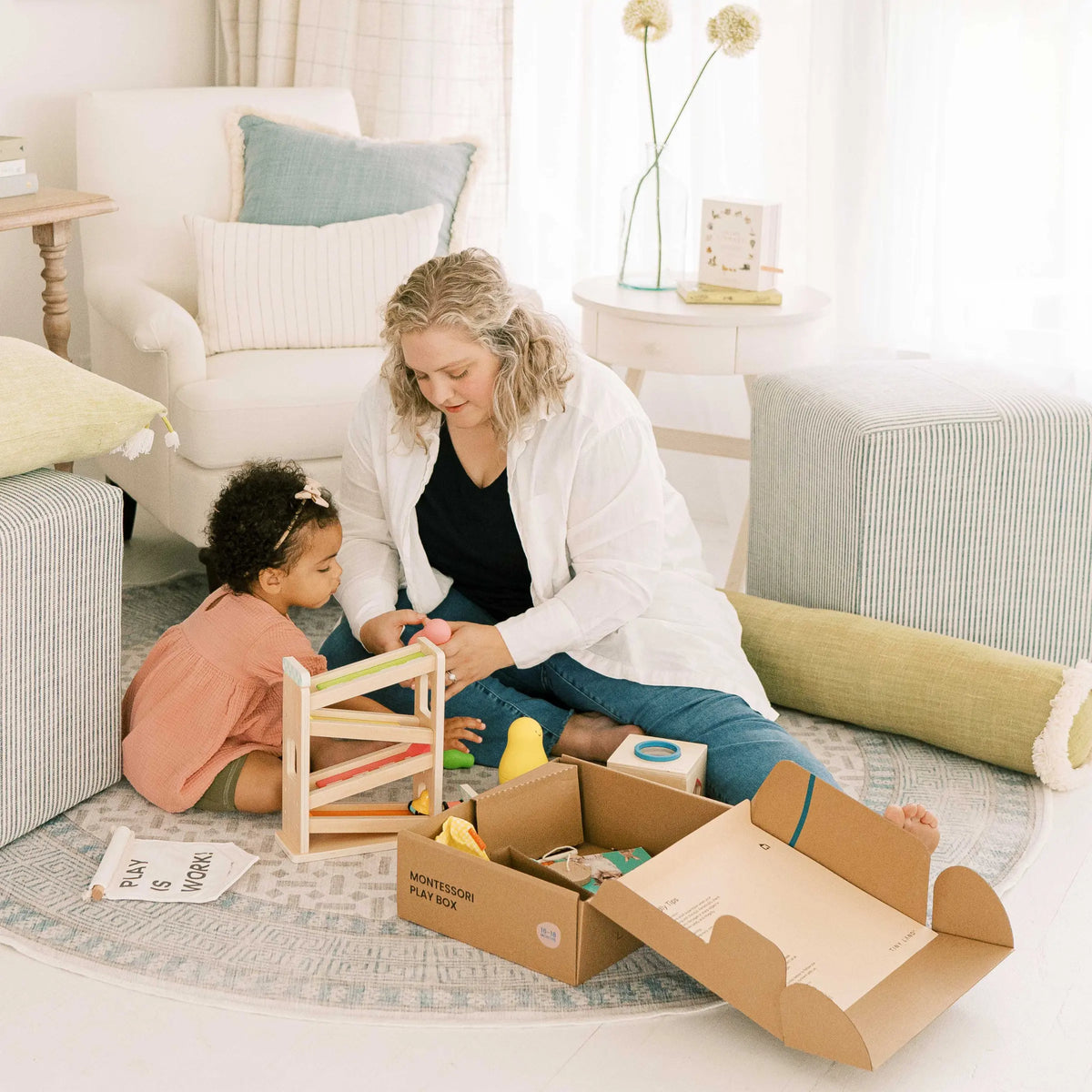 An adult and a young child assemble the Tiny Land® Montessori Toys for Toddlers (16–18 Months), surrounded by educational toys in a cozy, sunlit living room—perfect for curious minds.