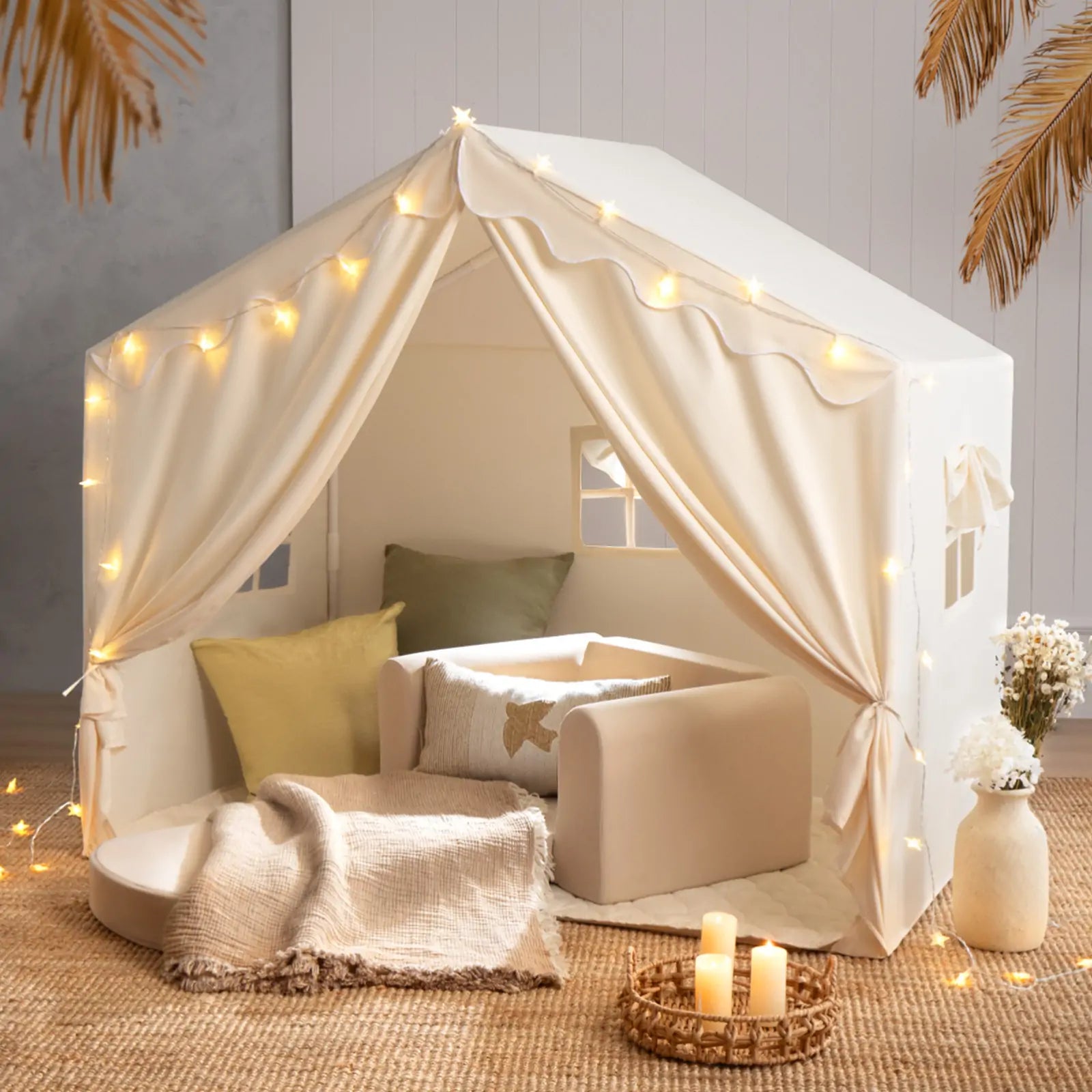 The Tiny Land® Kids Tent – Large Cozy Tent with Star Lights by Tiny Land features soft pillows, a blanket, and a small sofa on a woven rug, creating a warm, inviting atmosphere perfect for kids to play and relax.