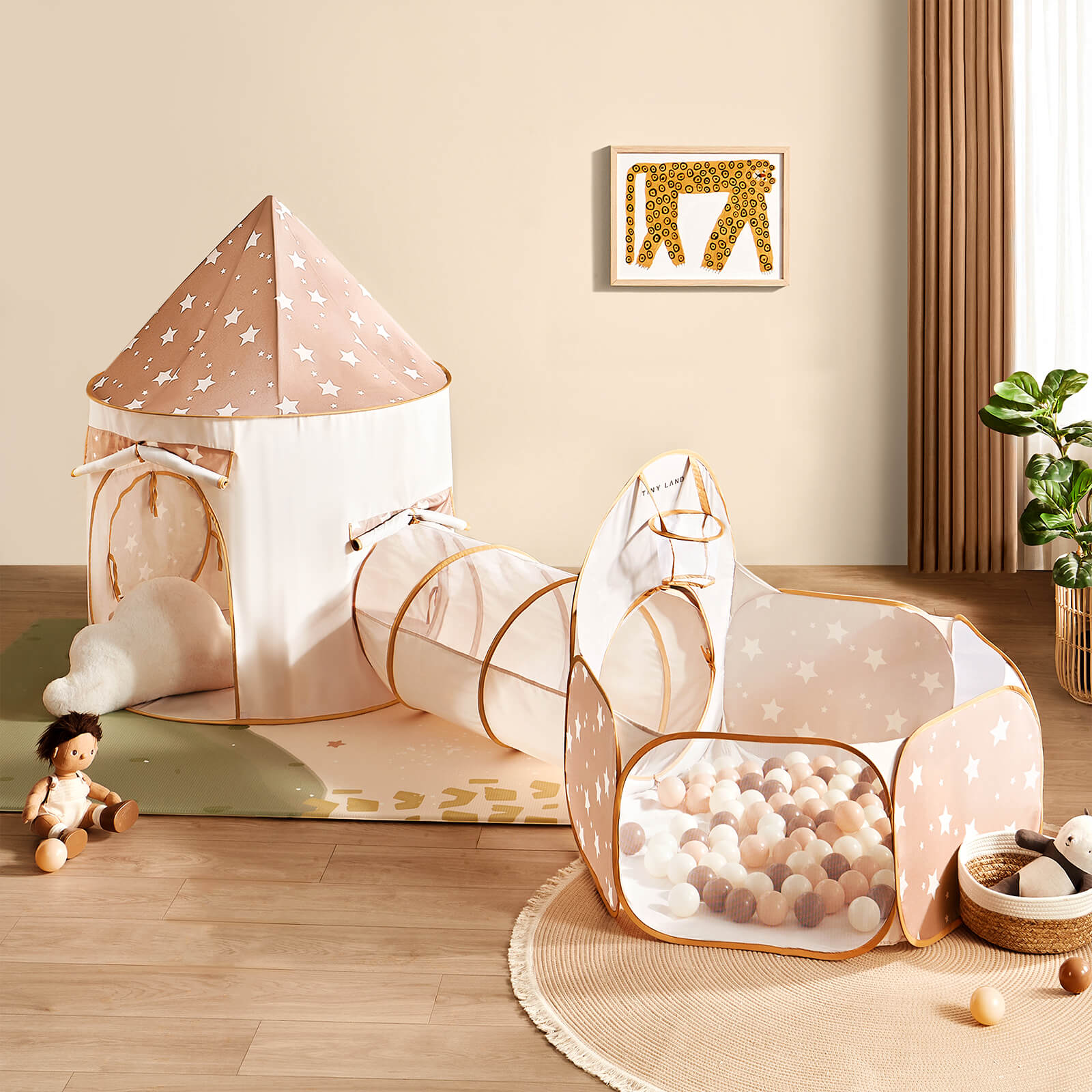 The Tiny Land® Compact Adventure 3-in-1 Play Tunnel, featuring a beige tent with white stars and a ball pit (no balls), is arranged on a mat in a cozy room. A brown-haired doll, plush carrot, and toys sit nearby as sunlight streams in.