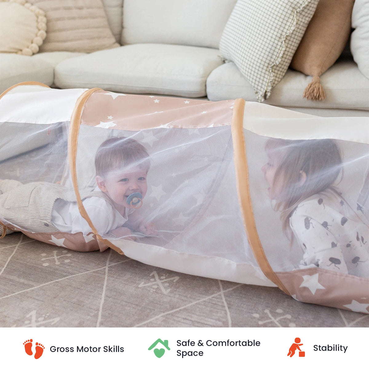 Two small children crawl through the Tiny Land® Adventure Play Tunnel by Tiny Land on a carpeted floor, with pillows and a couch in the background. This versatile play tunnel is perfect for both indoor and outdoor fun. Icons below highlight its support for gross motor skills, safety, and stability.|brown