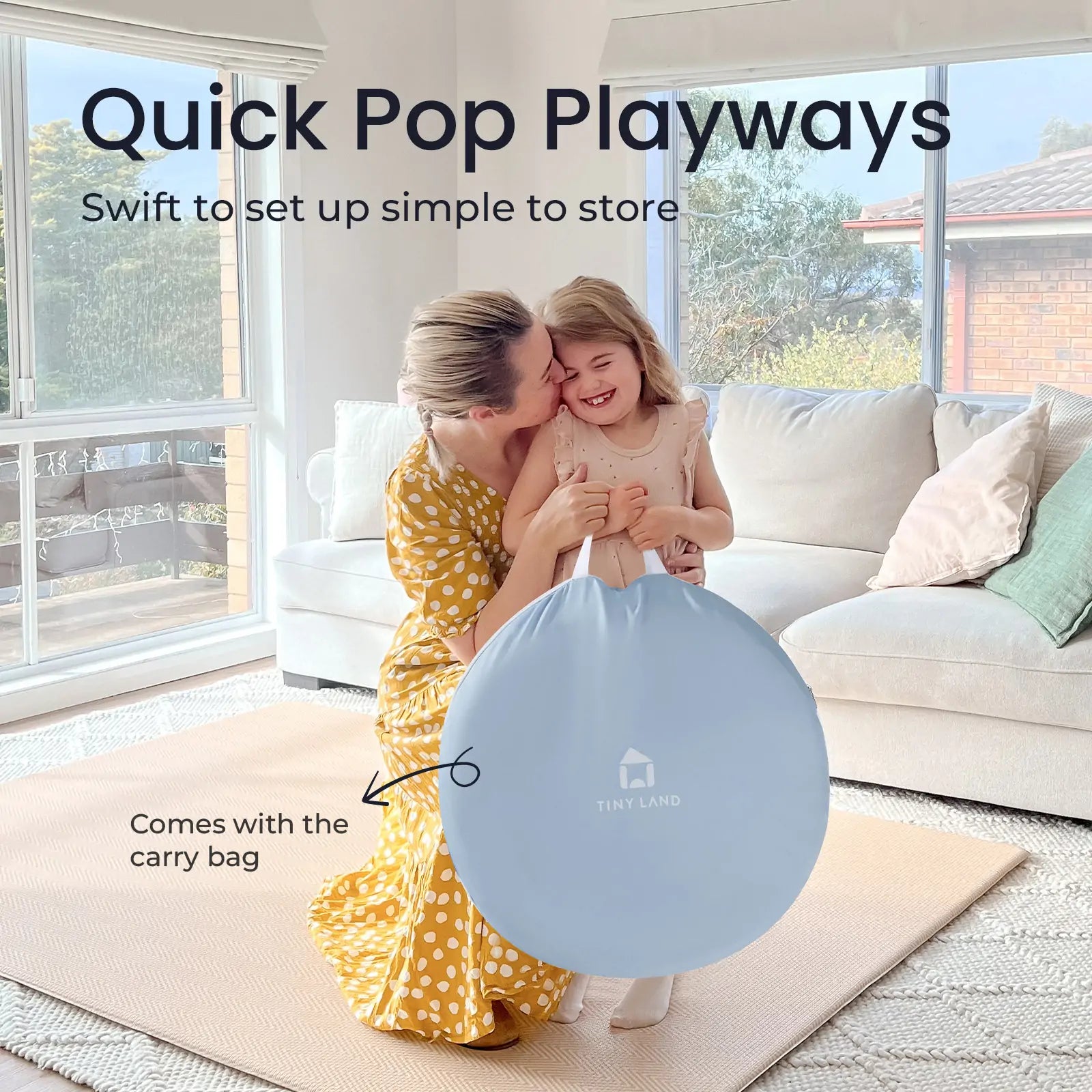 A smiling woman in a yellow dress hugs a young girl indoors as they hold the blue Tiny Land® Adventure Play Tunnel bag. Text reads: Quick Pop Playways—swift setup, easy storage, and includes the carry bag by Tiny Land.