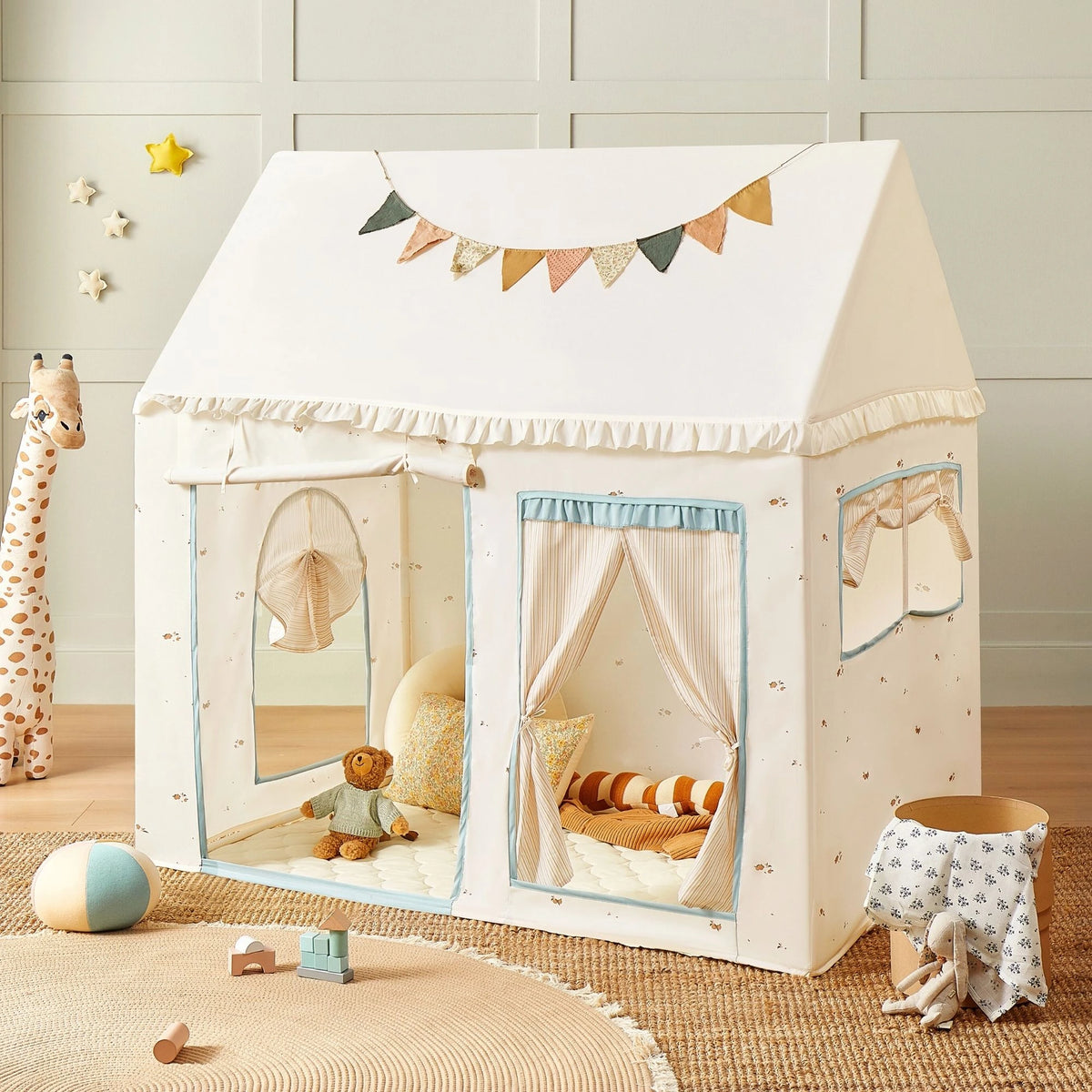The Tiny Land® Sweet Citrus Kids Play Tent is a white and blue indoor playhouse by Tiny Land, featuring pastel bunting, cushions, stuffed toys, and a giraffe toy—perfect for cozy kids’ play indoors or outdoors.