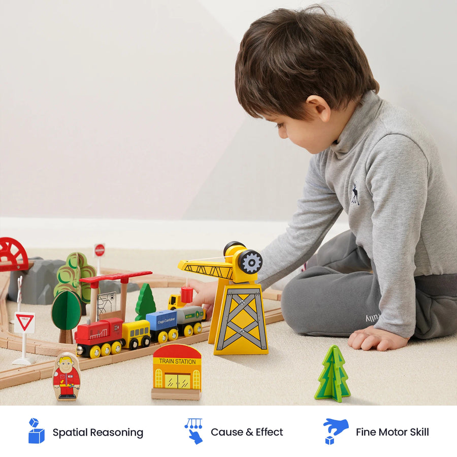A young child sits on the floor playing with the Tiny LandĀ® Wooden Train Set for Children by Tiny Land, crafted from sustainable wood. Icons and text below highlight benefits: Spatial Reasoning, Cause & Effect, and Fine Motor Skills. This train set is also compatible with popular wooden railway brands, providing endless opportunities for creative play.|55 Pcs