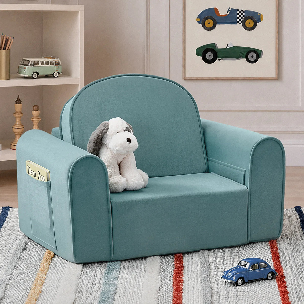 A Tiny Land® GentleSnug Kids Sofa Chair in light blue sits on a striped rug in a children’s room, accompanied by a stuffed dog toy. The inviting space features playful playroom furniture, including toy cars, bookshelves, and car-themed wall art in the background.|Blue