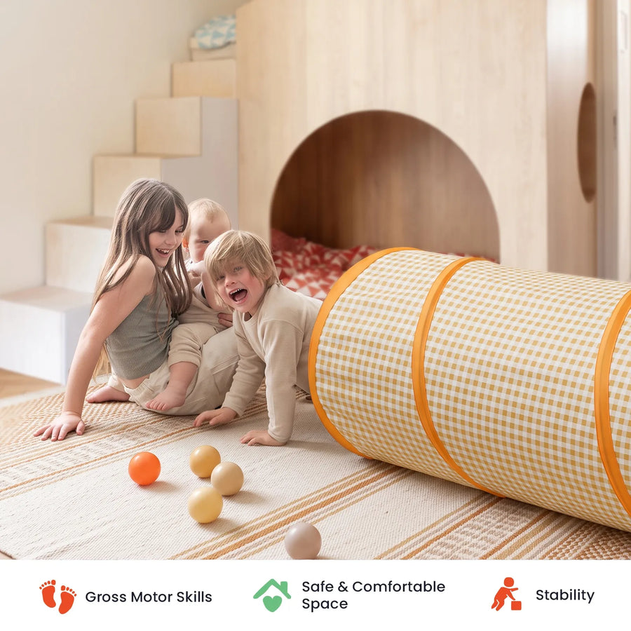 Three children play on a rug with a yellow and white gingham Tiny Land® Adventure Play Tunnel and small balls.|Yellow