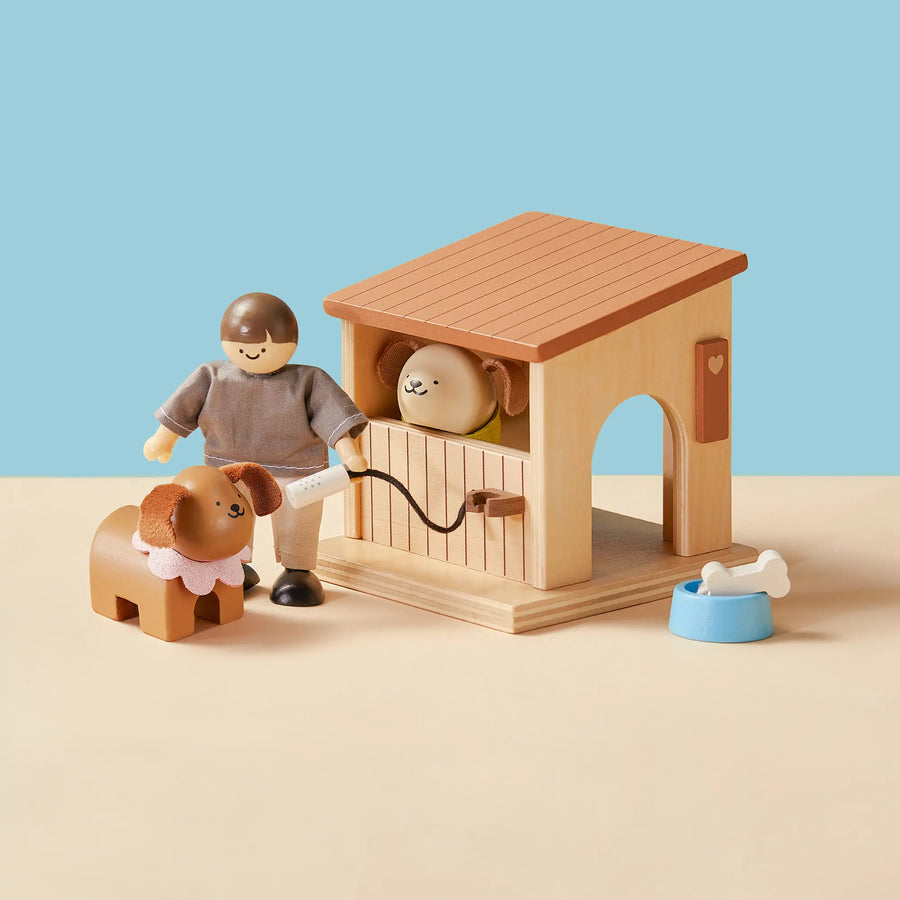 Transform your space with Tiny Land® Happy Urban Paws by Tiny Land—a wooden pet play set featuring a figure with a leash, dog, doghouse with pup, blue food bowl, and white bone, all arranged on a beige surface against a blue background.