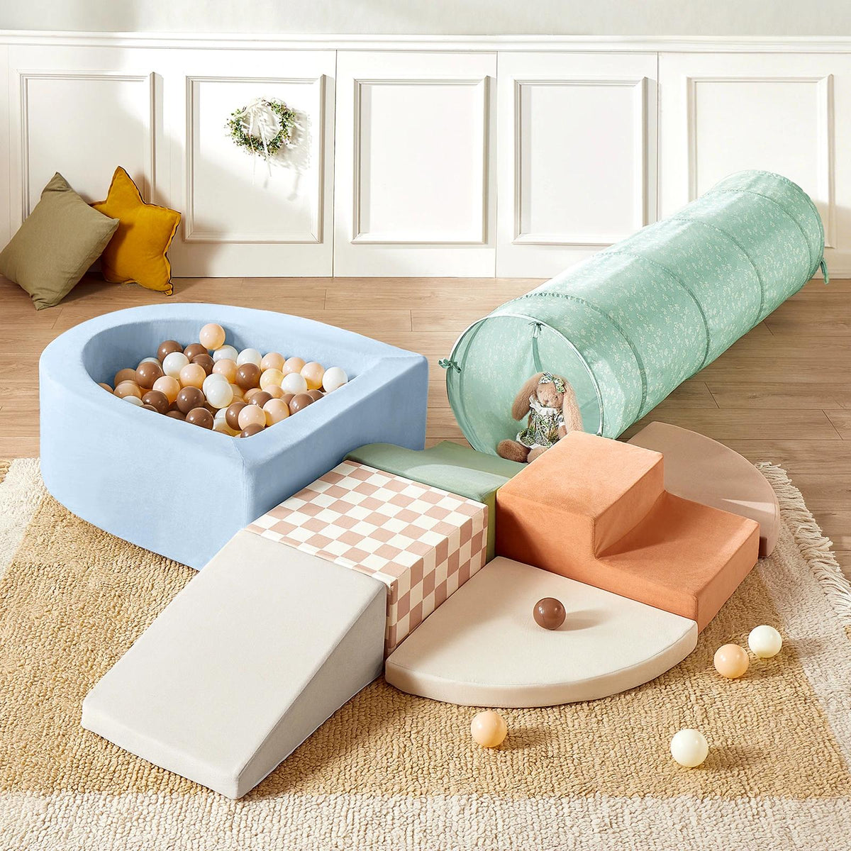 The Tiny Land® PlayNest Climbing Ball Pit Set with Tunnel by Tiny Land INC features a light blue foam ball pit with brown, tan, and white balls, a pastel green tunnel, climbing blocks, and foam steps on a beige rug.|blue