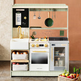 The Tiny Land® BistroSwitch Play Kitchen by Tiny Land features a sink, stove, oven, and fridge, plus pots, utensils, a chalkboard above, and baskets of play food and groceries arranged below—perfect for pretend play.|Green