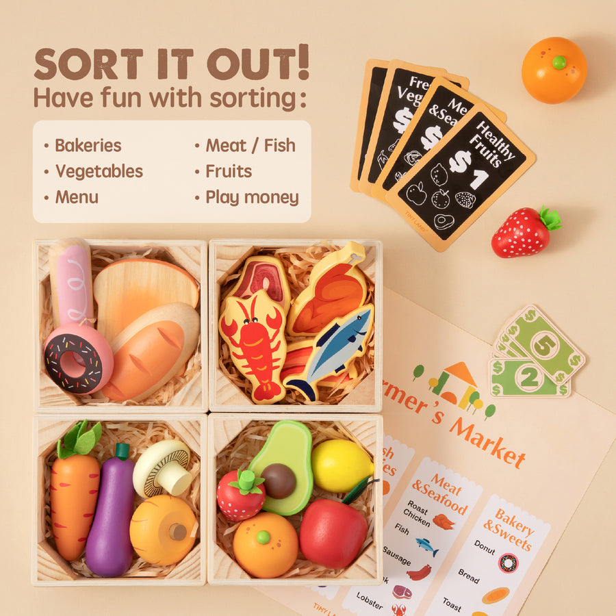 A flat lay features the Tiny Land Play Food – Play Kitchen Accessories set, including wooden bread, veggies, fish, play money, and cards for sorting—next to a "SORT IT OUT!" sign for fun bakery and market pretend play.