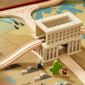 The Tiny Land® 1920 Railway Adventure Train Table by Tiny Land INC includes a wooden toy train, tracks passing through Union Station, two figures, a green tree, and a map play mat—ideal for creating an interactive city playset.