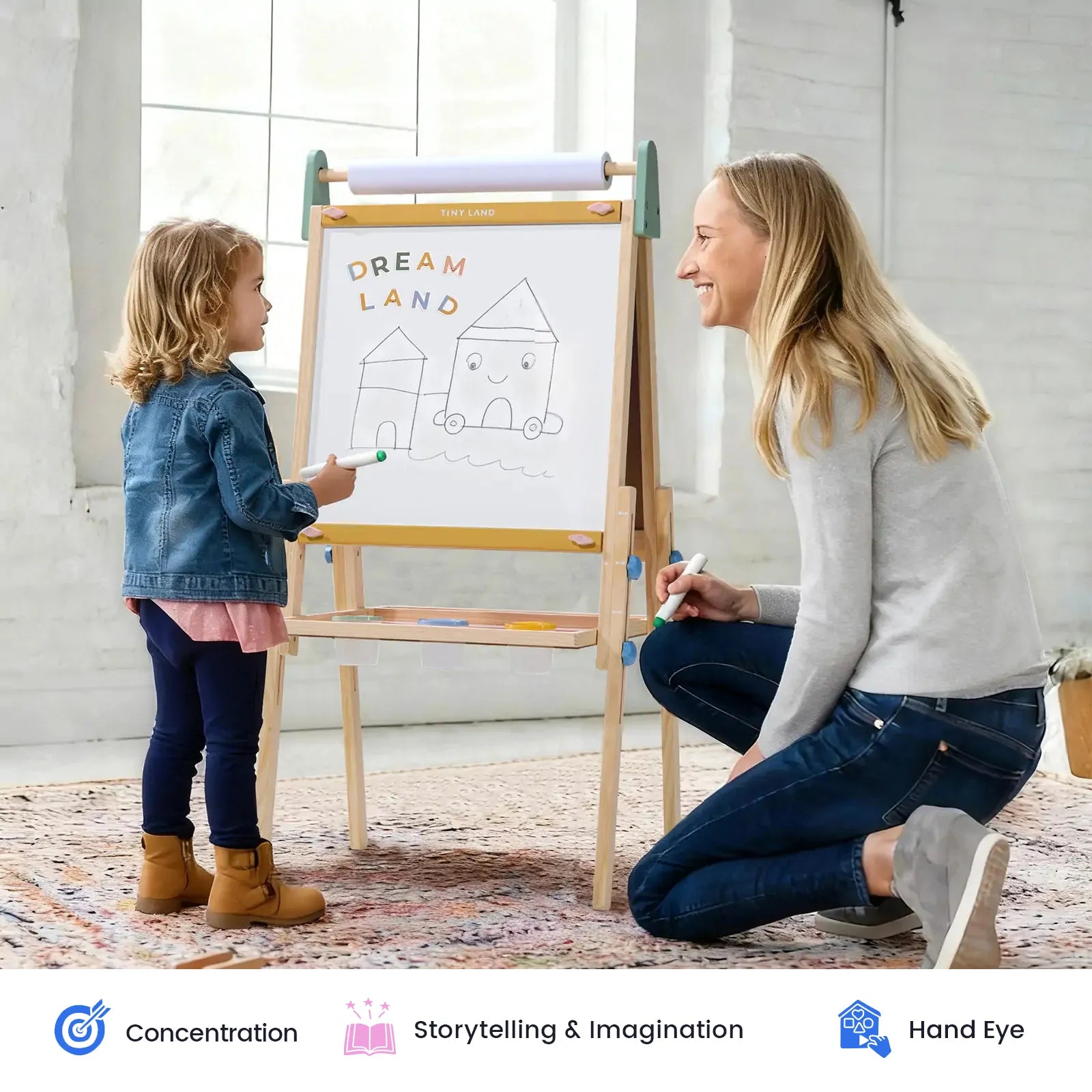 A woman kneels next to a young girl who is drawing houses on the Tiny Land® 3-in-1 Art Easel for Kids & Paper Roll Set by Tiny Land, with a whiteboard labeled “Dream Land” set on its adjustable height frame. Both are smiling in a bright room. Icons below highlight benefits such as enhancing concentration, fostering storytelling skills, and promoting hand-eye coordination.|green