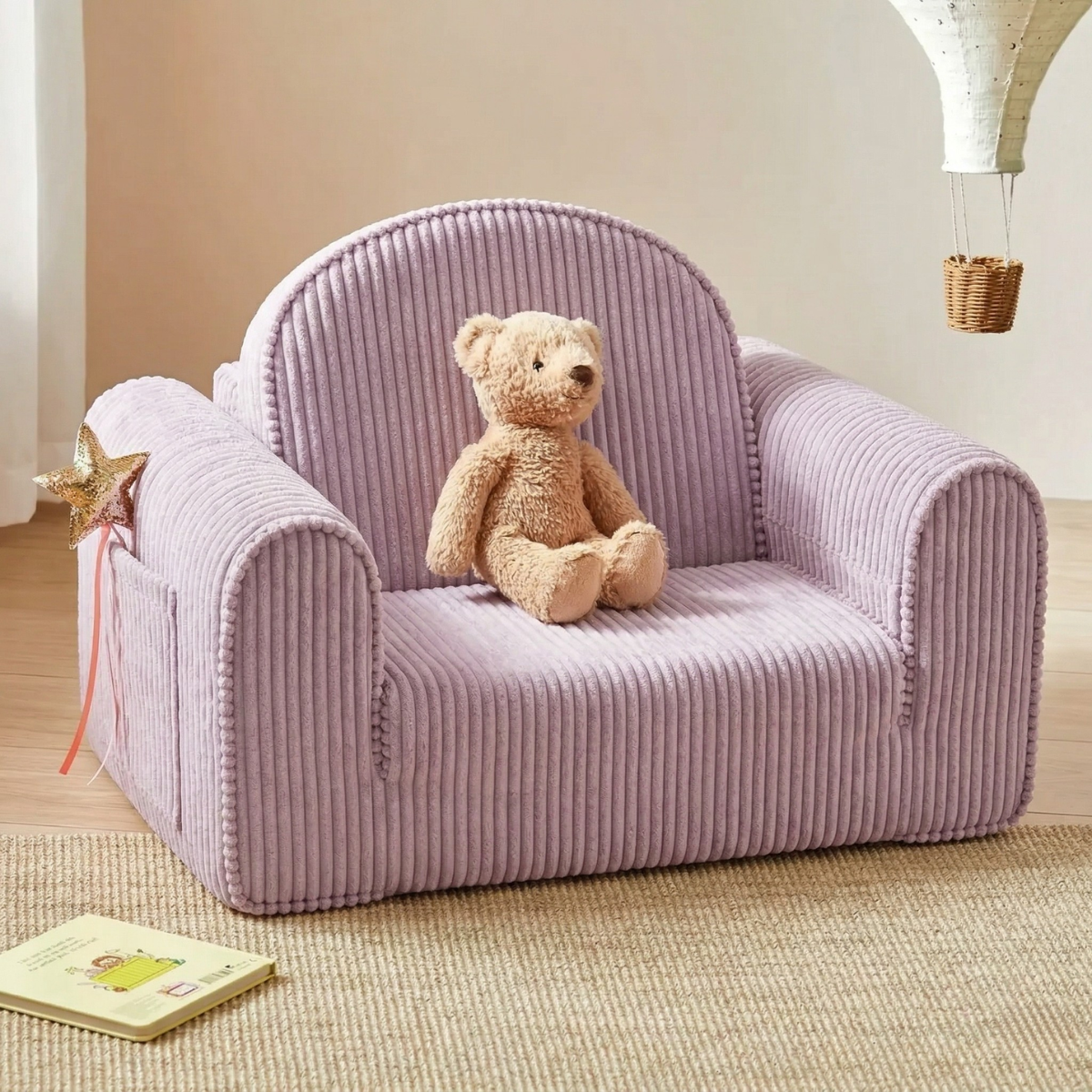 The Tiny Land® GentleSnug Kid Chair in light purple corduroy doubles as a sofa bed, shown with a beige teddy bear, star wand, and book in a cozy neutral-toned kids' room.