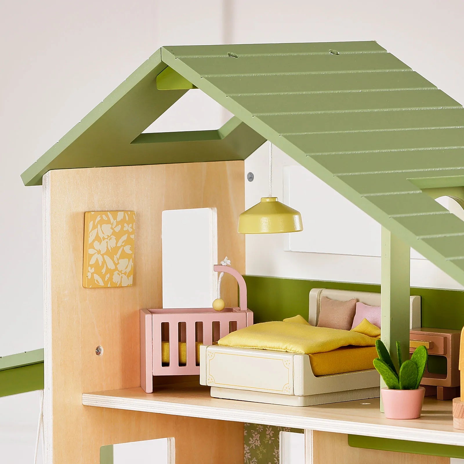The Tiny Land® Sweetwood Cottage Dollhouse by Tiny Land features a cozy, modern bedroom with a green roof, yellow-bedding bed, pink crib, small lamp, plant, and wall art.|Green