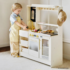 A young child wearing an apron and name tag enjoys pretend play with the Tiny Land® BistroSwitch Play Kitchen, cooking with play food and utensils. A cap hangs on the side of the white Tiny Land set.|White