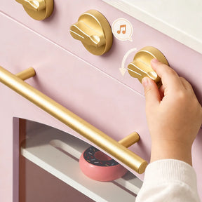 A child’s hand turns a gold oven knob on the Tiny Land® Wooden Play Kitchen with Storage for Creative Toddlers, where pretend cookware and a pink toy donut are visible inside the multifunctional storage oven.|Sakura Pink