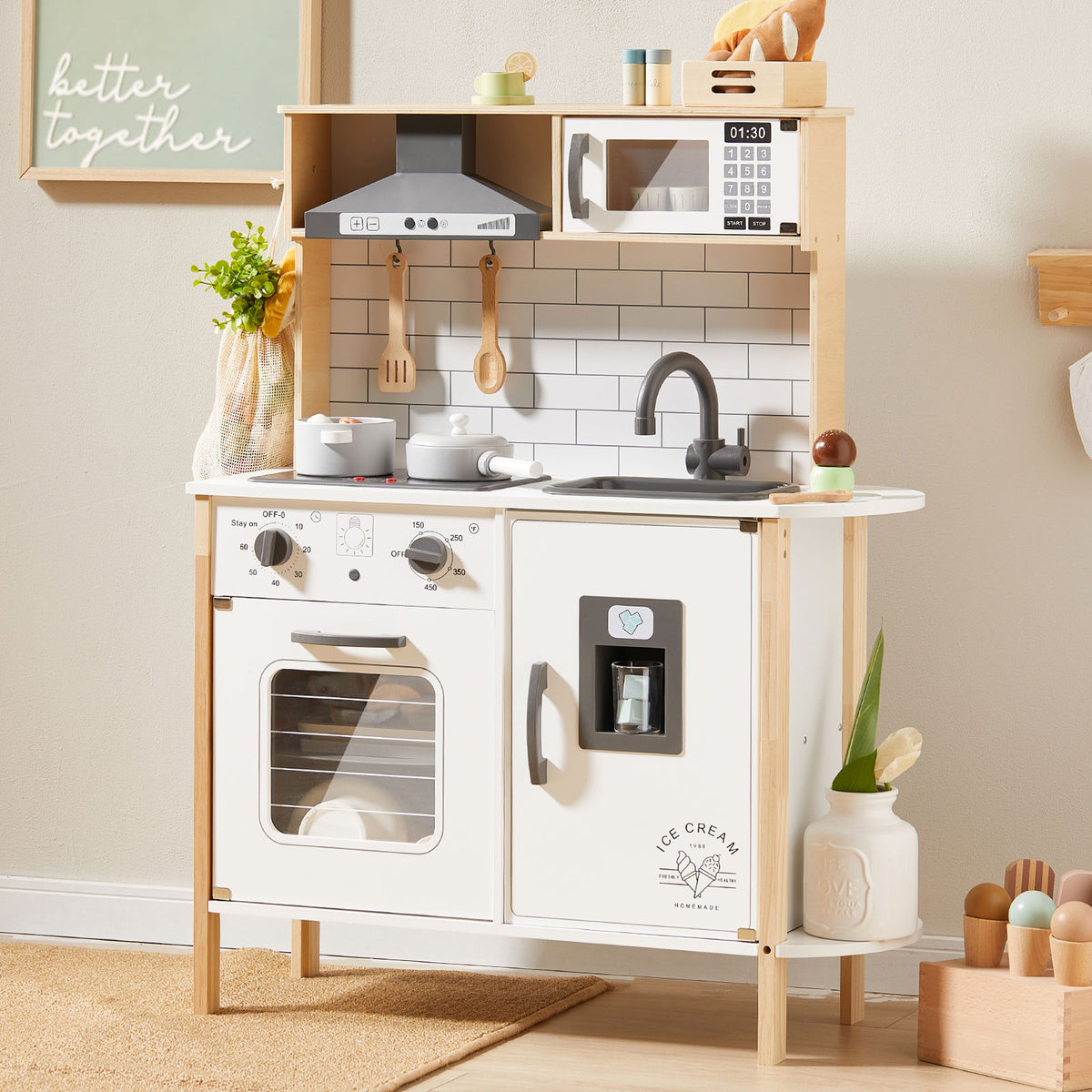 The Tiny Land® Interactive Play Kitchen with Sounds & Cookware features a stove, oven, sink, microwave, utensils, and toy food. “Better together” is written above, with charming plant and flower decorations from Tiny Land.