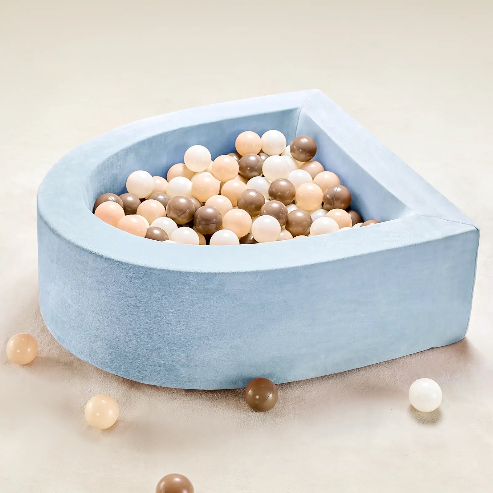 The Tiny Land® Blue PlayNest Ball Pit by Tiny Land INC features a soft, semi-circular design in light blue, filled with 200 beige, white, and brown ocean balls, with several balls scattered on a light-colored surface.|blue