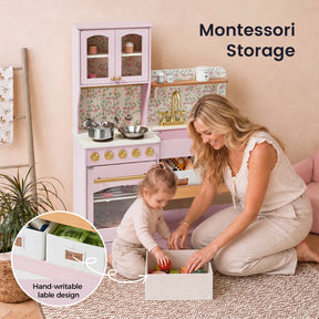 A woman and a young child play with the Tiny Land® Wooden Play Kitchen with Storage for Creative Toddlers by Tiny Land. An inset highlights a drawer featuring hand-writable labels. Text reads Montessori Storage. The scene appears calm and organized, emphasizing educational play and multifunctional storage solutions.|Sakura Pink
