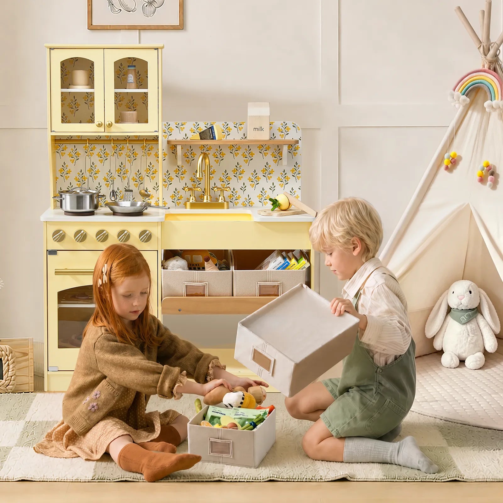 Two young children sit on a rug in a playroom decorated in soft pastel colors, organizing stuffed animals and toys into storage boxes beside the Tiny Land® Wooden Play Kitchen with Storage for Creative Toddlers by Tiny Land and a small tent. Pretend cookware enhances the imaginative atmosphere as they play.|Pale Yellow