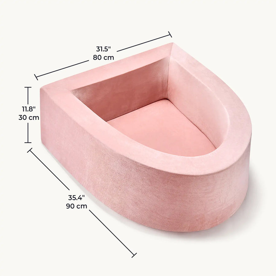 The Tiny Land® PlayNest Soft Foam Ball Pit by Tiny Land is a pink, velvet, U-shaped pet bed with high sides—ideal for sensory play or as a cozy ball pit for your furry friend. Measuring 35.4" (90 cm) long, 31.5" (80 cm) wide, and 11.8" (30 cm) high, the product image features black measurement lines and numbers for reference. Balls not included.|Pink
