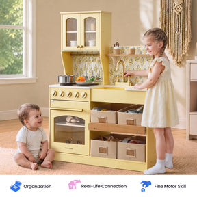 Two young children play with the Tiny Land® Wooden Play Kitchen with Storage for Creative Toddlers in a sunlit room. The older child stands and pretends to wash dishes using the included pretend cookware, while the younger child sits on the floor, smiling.|Pale Yellow