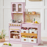 The Tiny Land® Wooden Play Kitchen with Storage for Creative Toddlers by Tiny Land comes in pink with gold accents and includes pretend cookware, toy food, pots, and labeled storage bins for meat, milk, tools, and fruit. Set against floral wallpaper for added charm, this multifunctional play kitchen features a sink, oven, stove, and thoughtful storage—while decorative flowers placed nearby complete the inviting scene.|Sakura Pink