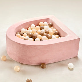 The Early Bird Eggs-Tiny Land® PlayNest Ball Pit by Tiny Land INC features a soft, pink, D-shaped design with 200 cream, brown, and white ocean balls. Several balls from this cozy play nest are scattered across the light beige floor.|pink