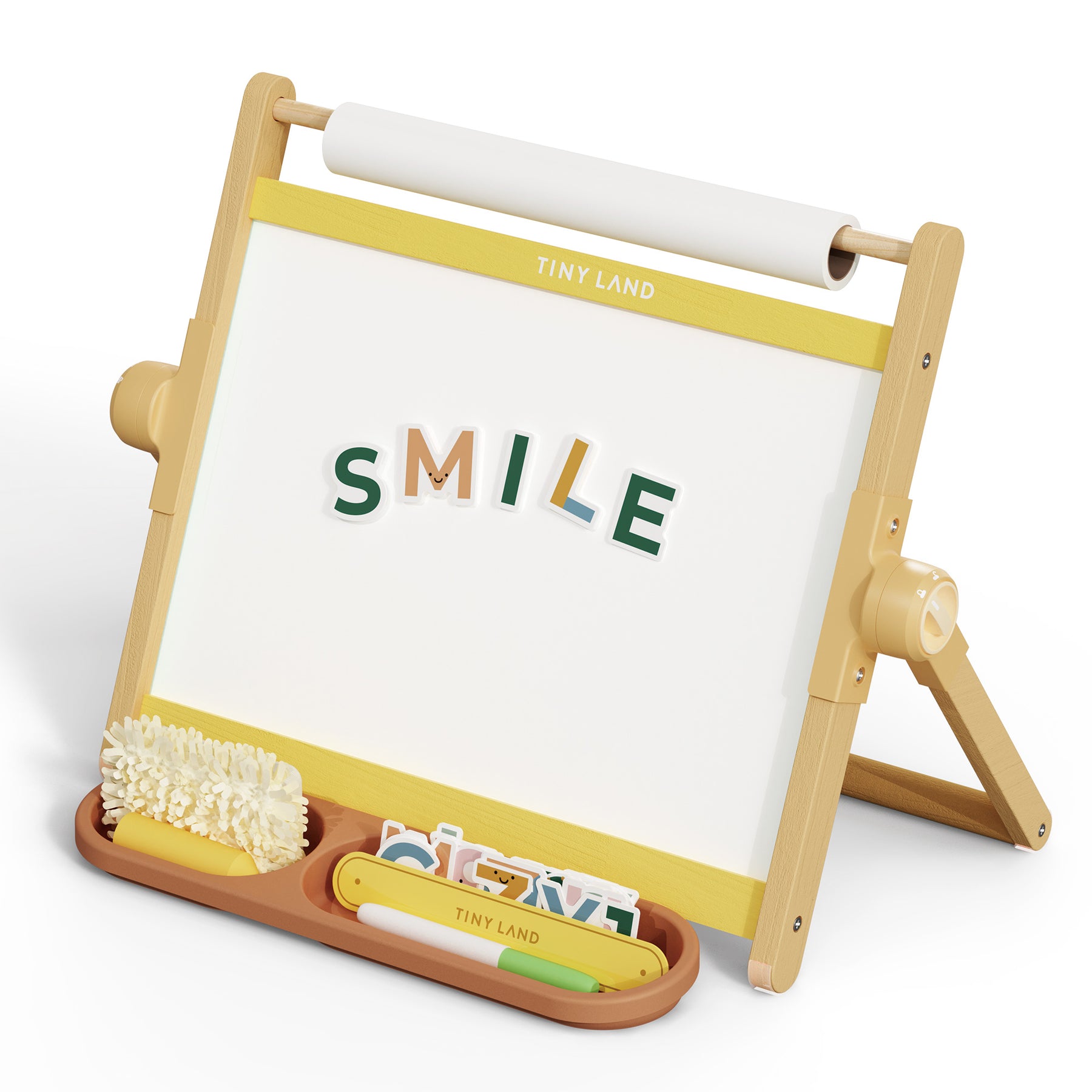 The Tiny Land® Double-Sided Magnetic Tabletop Easel - Yellow features a whiteboard with colorful magnetic letters spelling "SMILE," a tray for brushes, chalk, and erasers, and a roll of white paper for endless creativity.