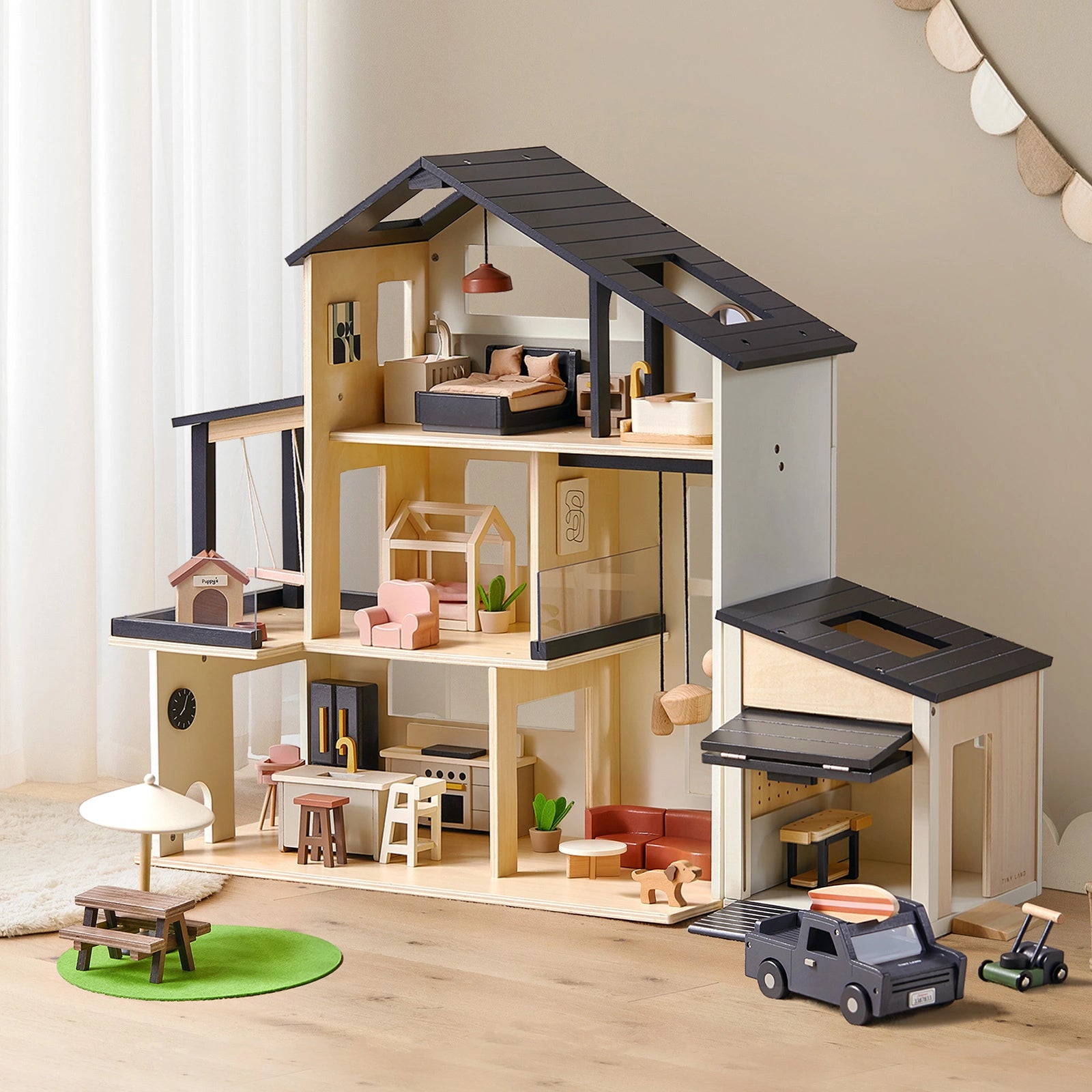 Tiny Land® Sweetwood Edge Dollhouse & Wooden Dollhouse Garage featuring multiple furnished rooms, an attached garage, a miniature picnic set on a green mat, a toy car, and a lawnmower.