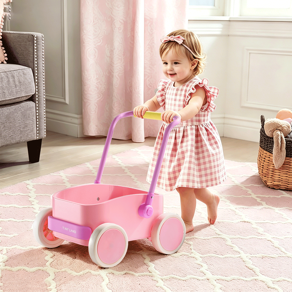 A toddler wearing a pink plaid dress pushes the Test Tiny Land® JoyRide Baby Walker with Blocks - Pink, featuring white wheels, across a soft, light pink patterned rug in a cozy, pastel-themed room.