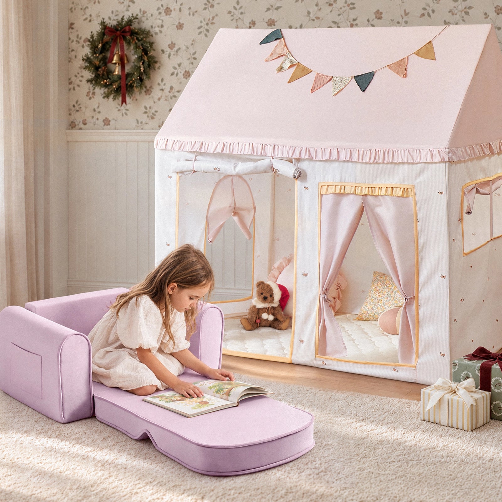 A young girl in a white dress reads a book while sitting on a lavender Tiny Land® Cozy Nook – Playhouse Tent & GentleSnug Kid Chair in front of a white and pink playhouse tent.|Pink